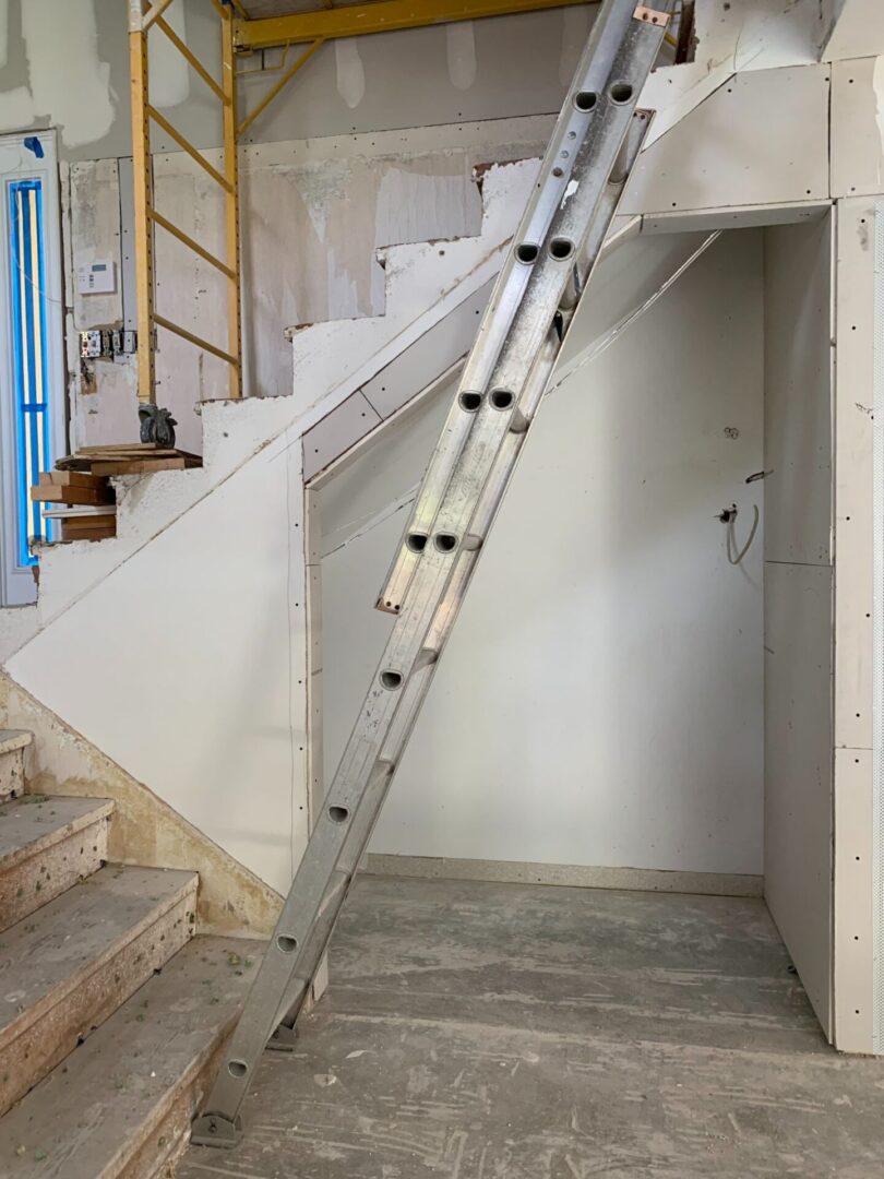 A ladder in a room that is under construction.