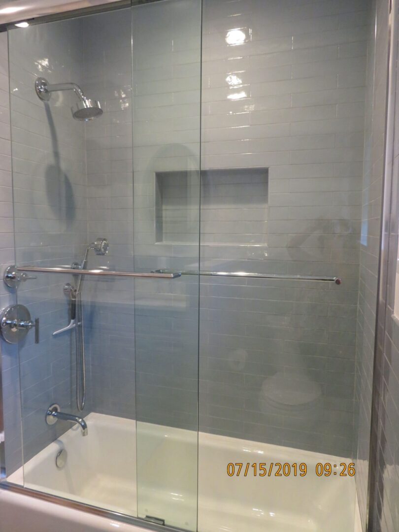 A glass shower with a tub and a toilet.