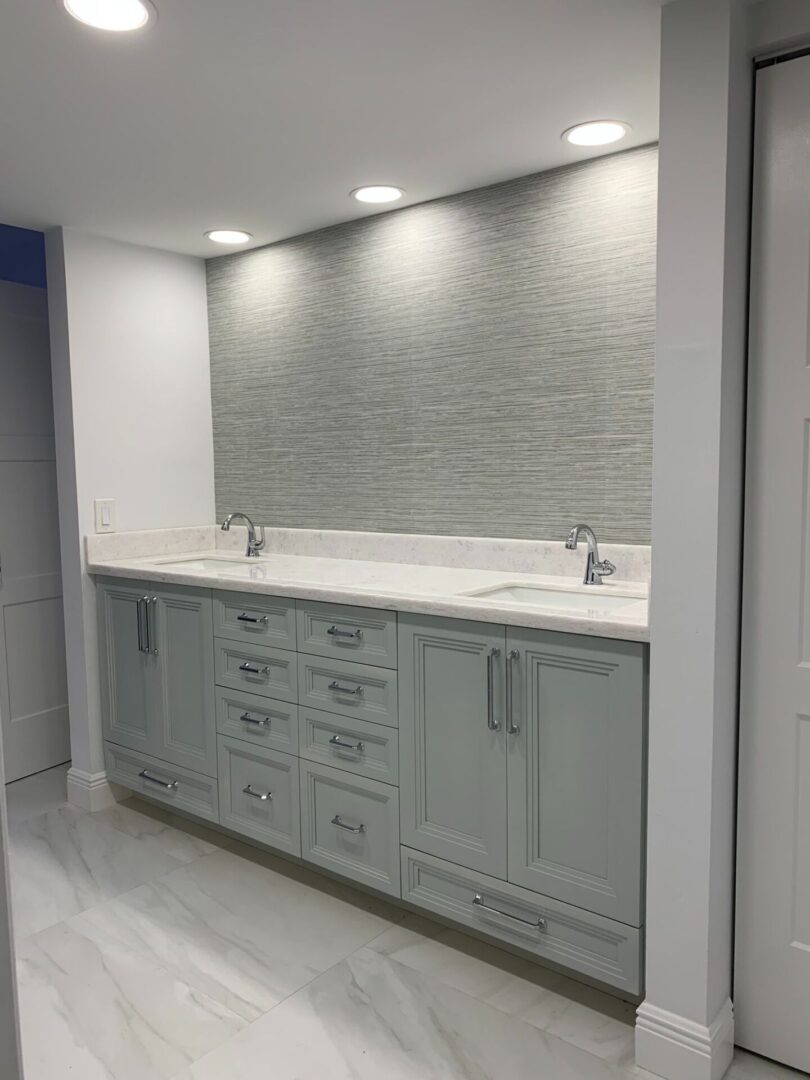 A bathroom with white cabinets and marble counter tops.